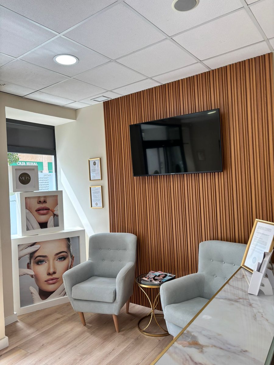 Sala de espera de Clínica METS Antequera con sillones y pared de listones de madera