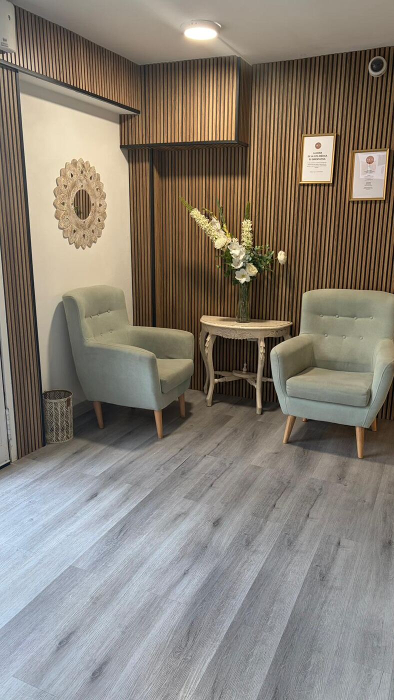 Sala de espera de Clínica METS Torremolinos con sillones verdes y listones de madera